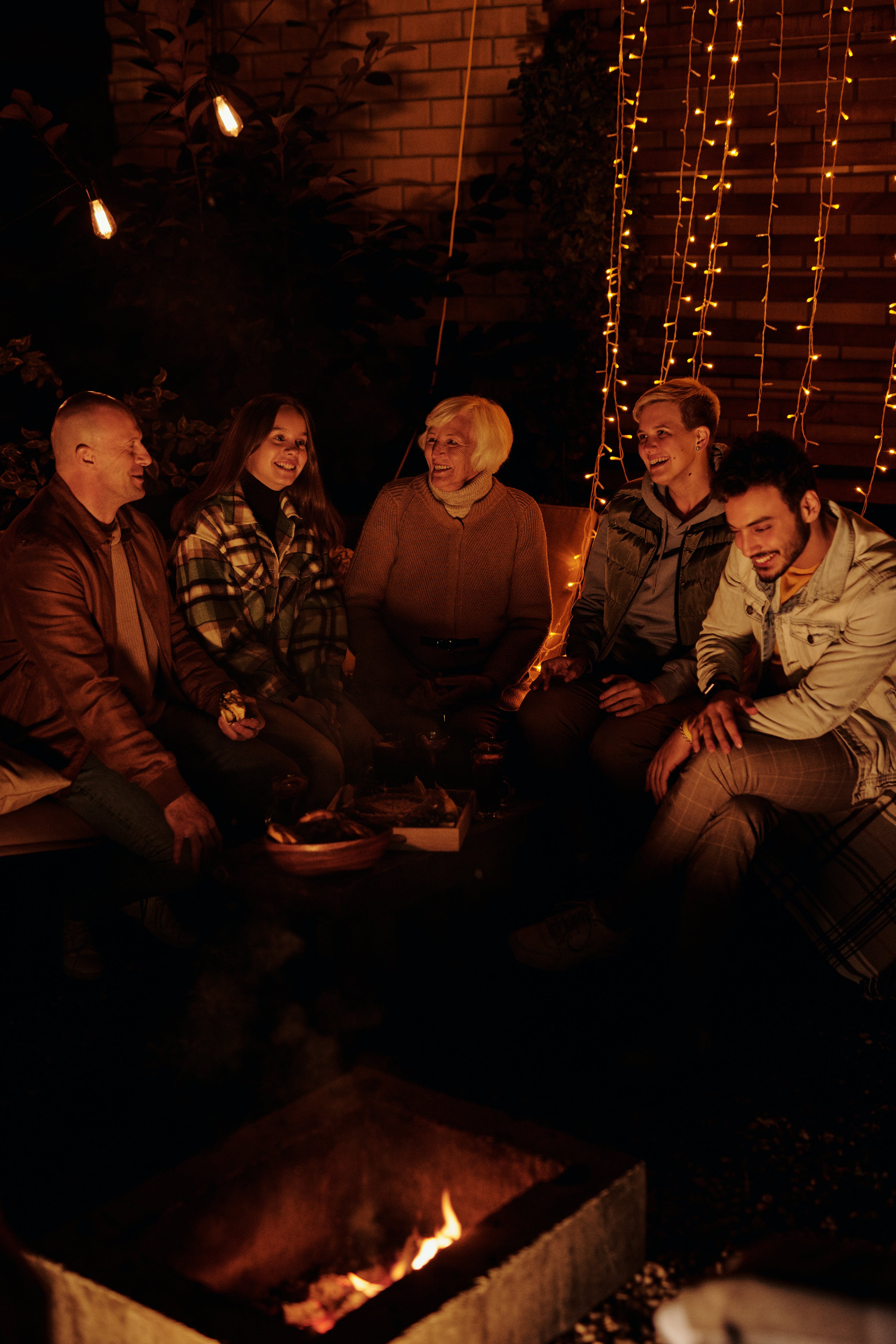 Family gathering around bonfire in dark backyard